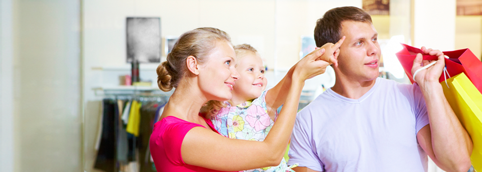 Parents and their child in a retail environment looking and pointing at a Save9 digital signage solution